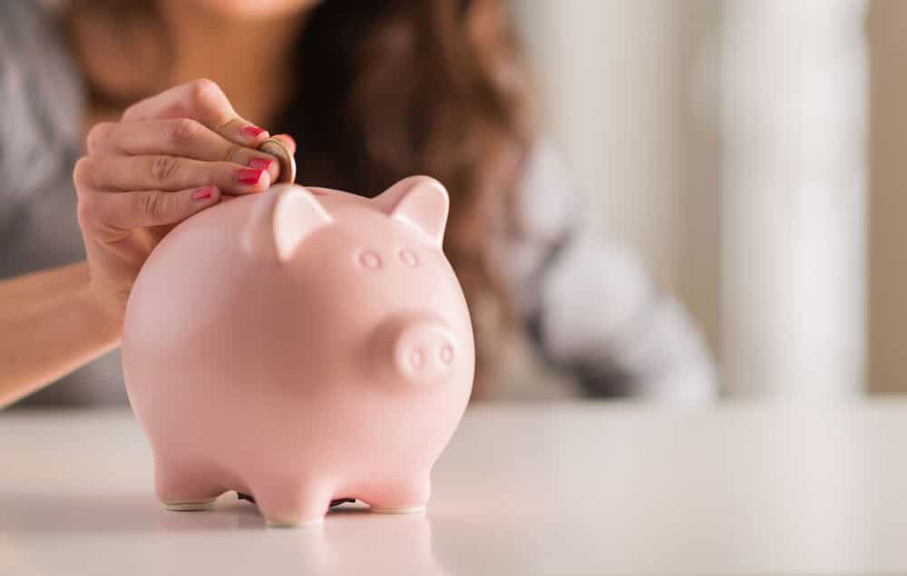 Woman dropping a coin into a piggybank