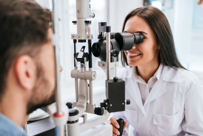 doctor looking at man's eye through testing machine