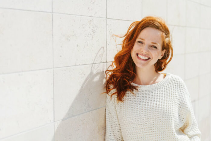 young woman with red hair leaning on wall