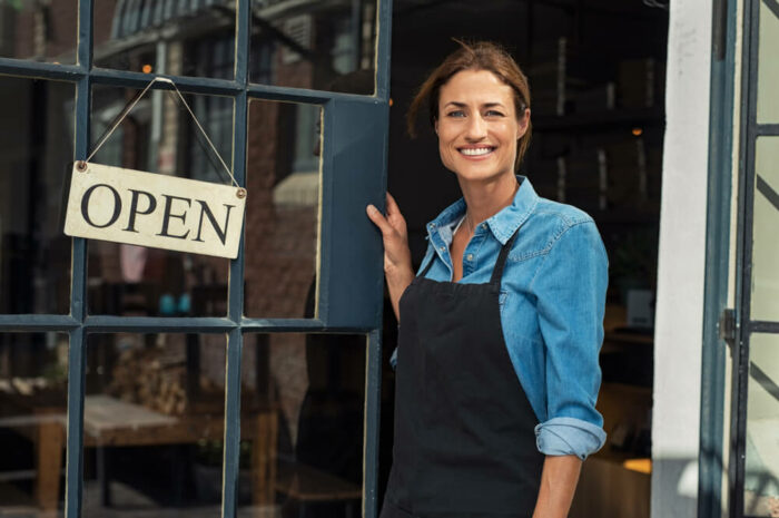 shopkeeper outside of store with open sign