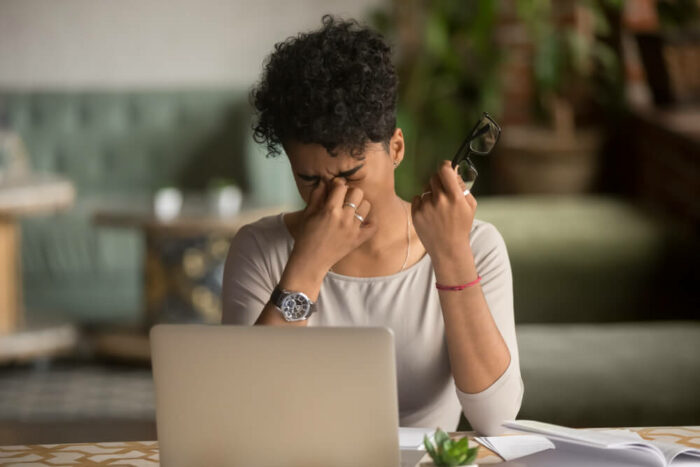 woman in front of laptop rubbing eyes